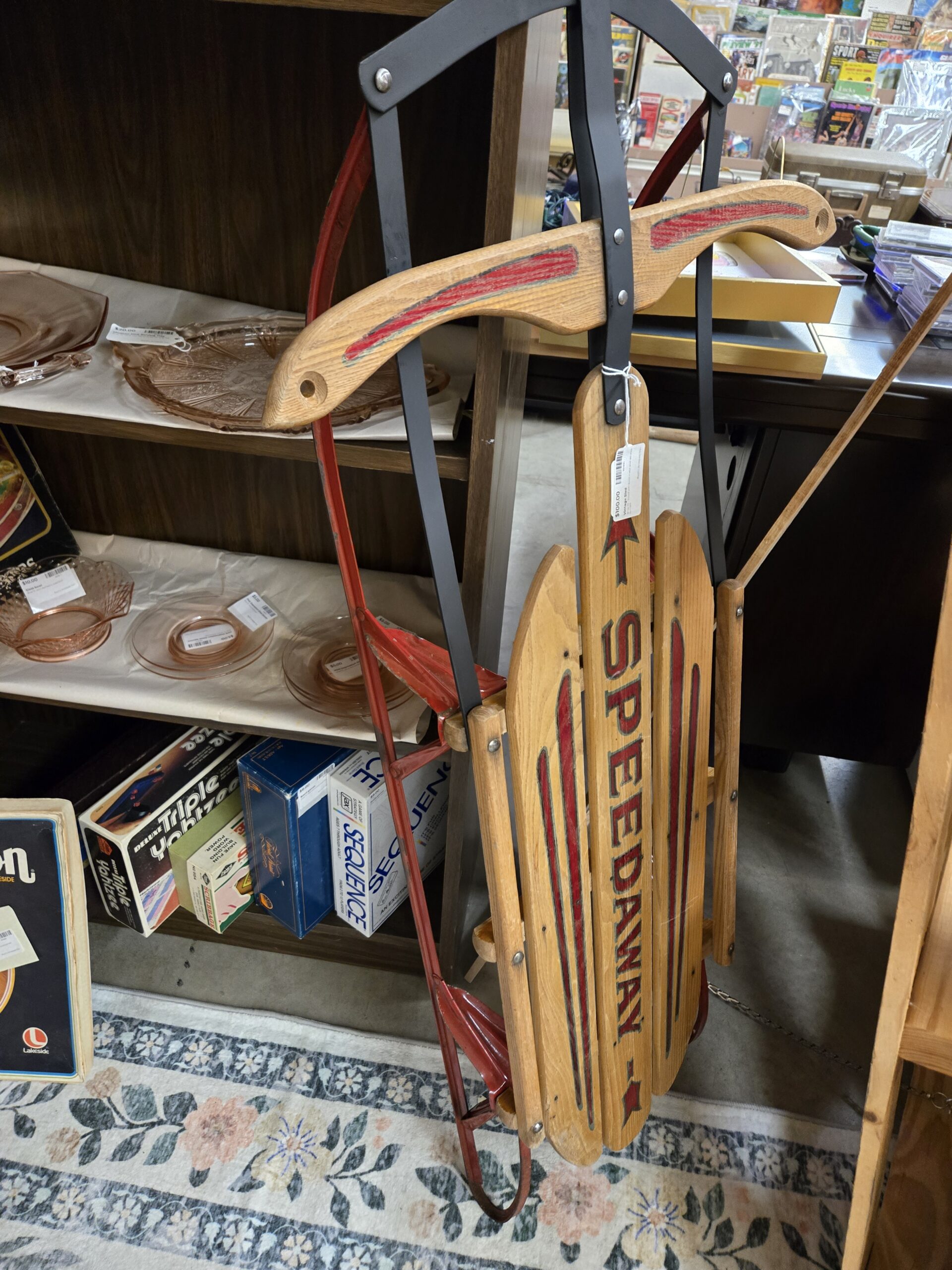 Vintage Speedaway wooden slat sled with red steel runners, a black steel steering frame, and a wooden crossbar trimmed in red paint, with red arrow and star graphics down the center slat, at Shop 73, Pacific Antiques Mall in Tacoma, WA.