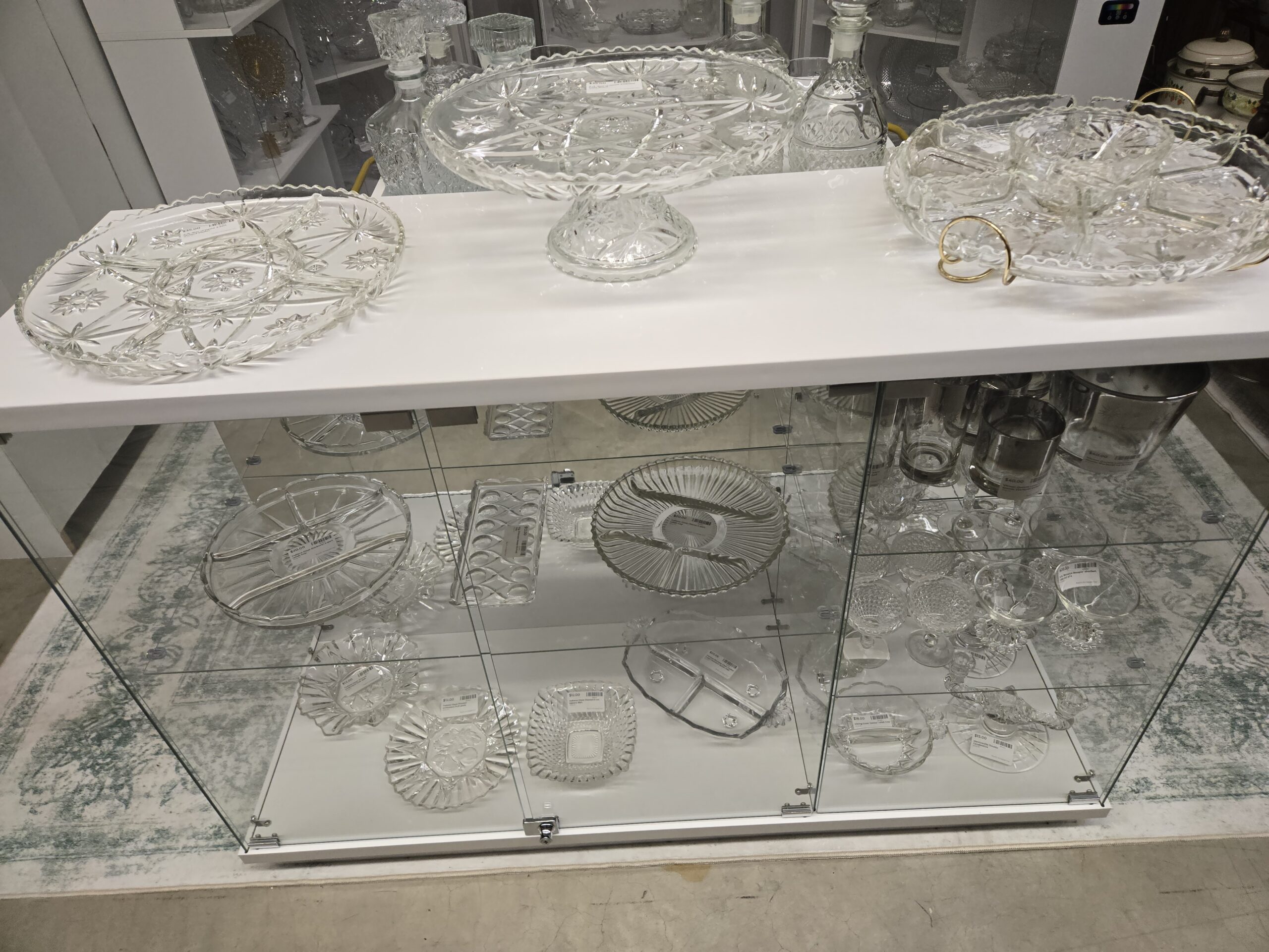 A Star of David divided relish platter, a footed oval cake plate in the star pattern, a relish set in a brass-tone stand, stoppered glass decanters, an Indiana Glass Starburst four-part relish tray, an Indiana Glass ribbed four-part relish tray, a pressed relish tray with oval cutouts, ruffled bowls, a square pressed bowl, a three-part handled relish dish, Anchor Hocking Berwick Boopie sherbets, silver-band glasses and a matching ice bucket, a Viking Janice relish tray, and a New Martinsville double candlestick at Shop 20, Pacific Antiques Mall in Tacoma, WA.