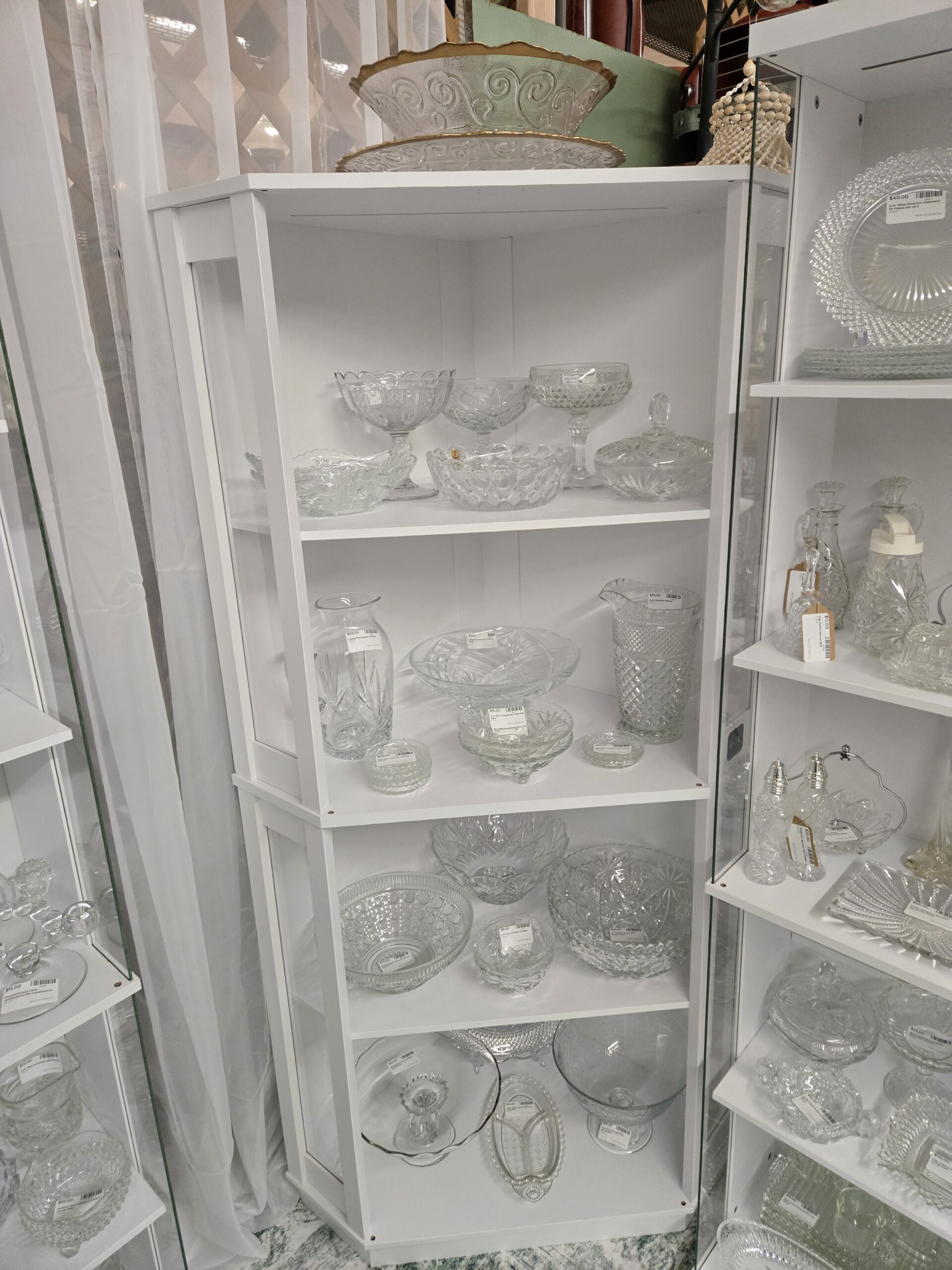Gold-rimmed embossed scroll bowl and platter, footed compotes in lattice, star and diamond point patterns, a covered candy dish, a crystal Pineapple pitcher, a Waterford Marquis crystal bowl, an Anchor Hocking Wexford pitcher, Star of David serving bowls and coasters, pressed glass fruit bowls, a gold-rimmed cake stand, a Hazel Atlas three-part relish dish, and a Southern Living at Home footed serving bowl at Shop 20, Pacific Antiques Mall in Tacoma, WA.